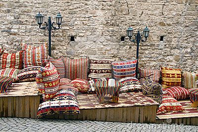 a bunch of pillows sitting on top of a wooden bench in front of a stone wall