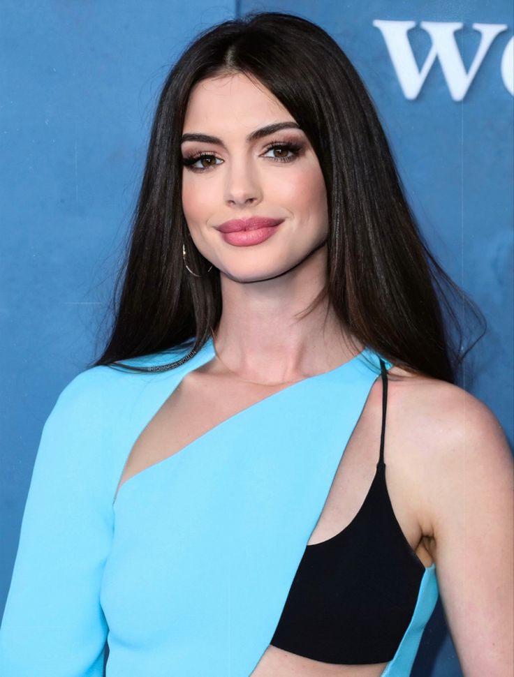 a woman with long dark hair wearing a blue top and black bra, posing for the camera