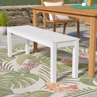 a white bench sitting on top of a rug next to a wooden table and chairs