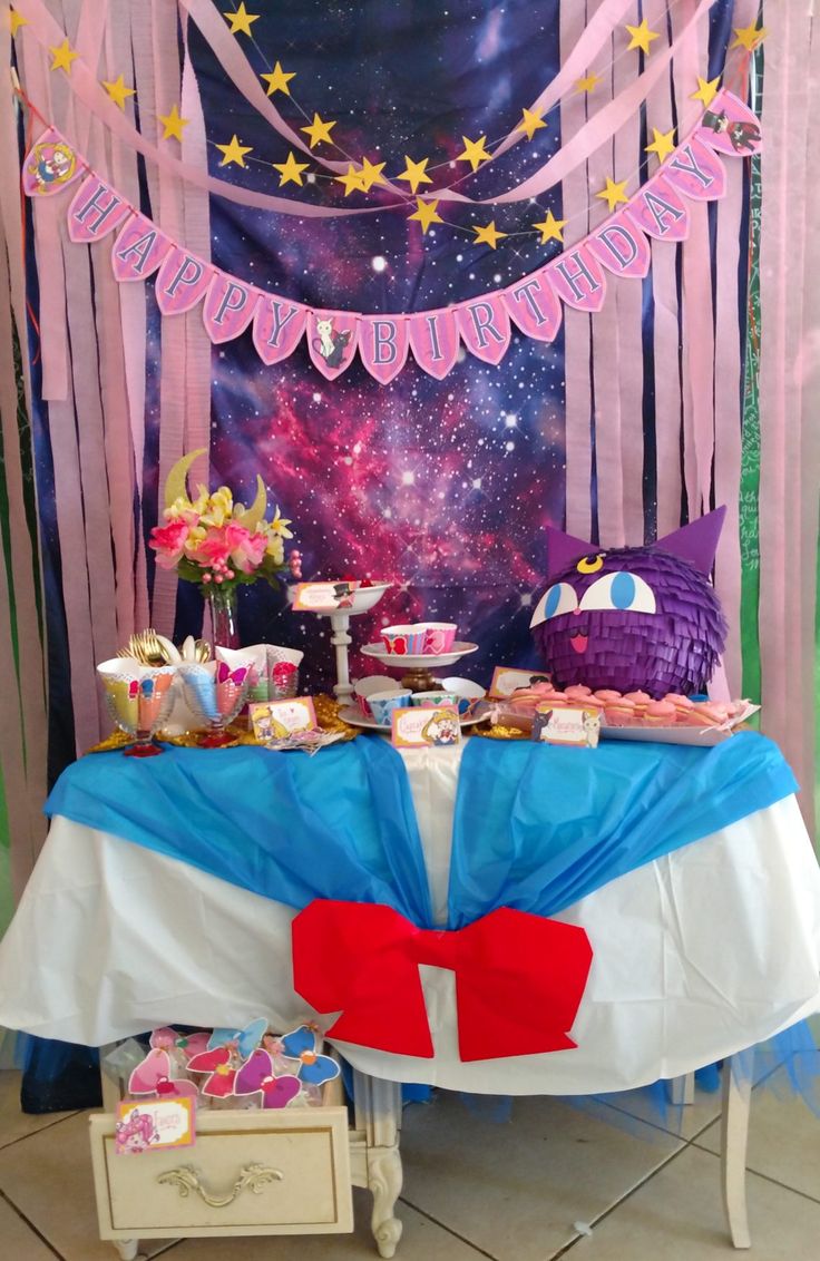 the table is set up for a party with pink and blue streamers, stars, and decorations