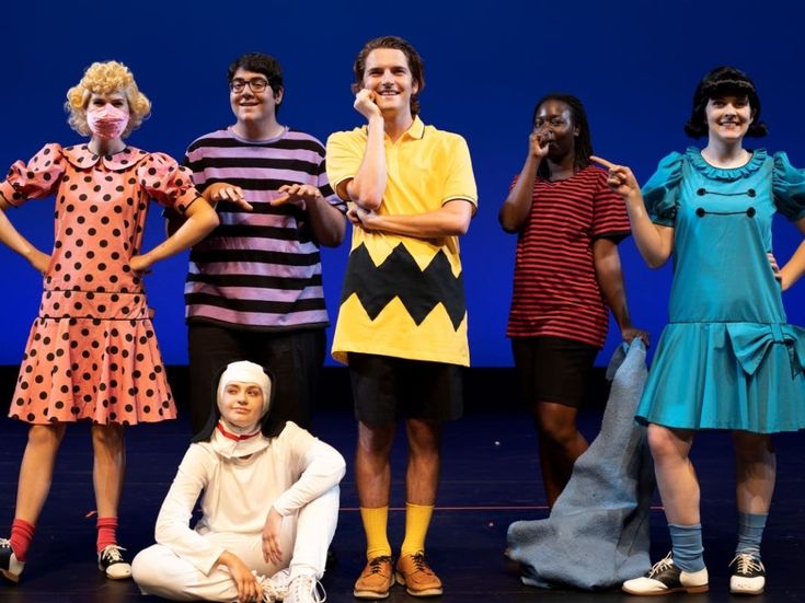 group of people dressed in costumes posing on stage