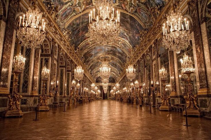 an ornate hall with chandeliers and paintings on the walls