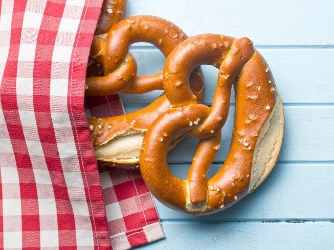 two pretzels are on a red and white checkered napkin next to a bagel