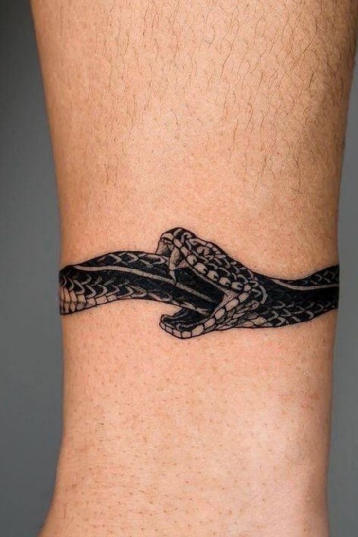 a black and white snake tattoo on the side of a man's lower leg