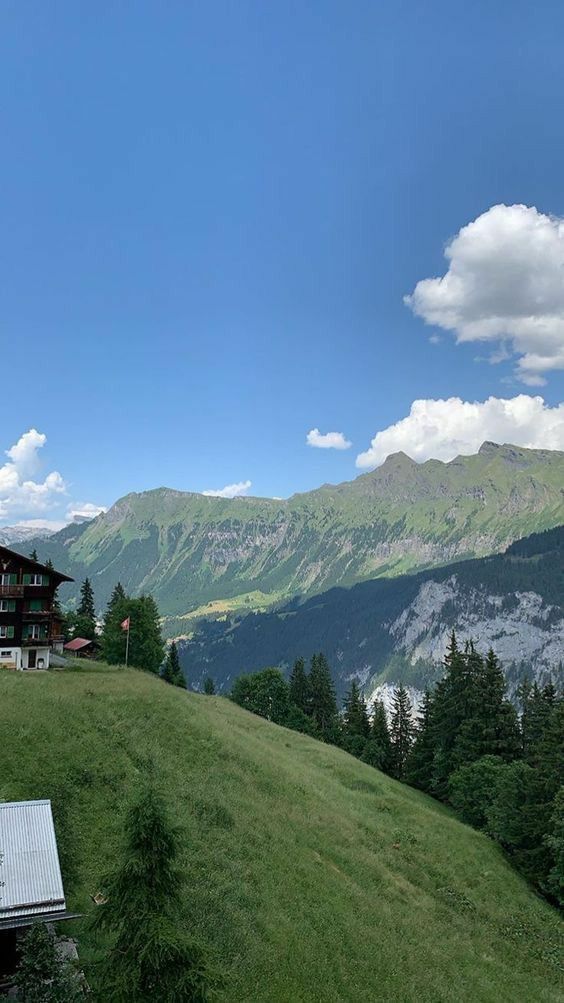 a house on top of a hill with mountains in the background