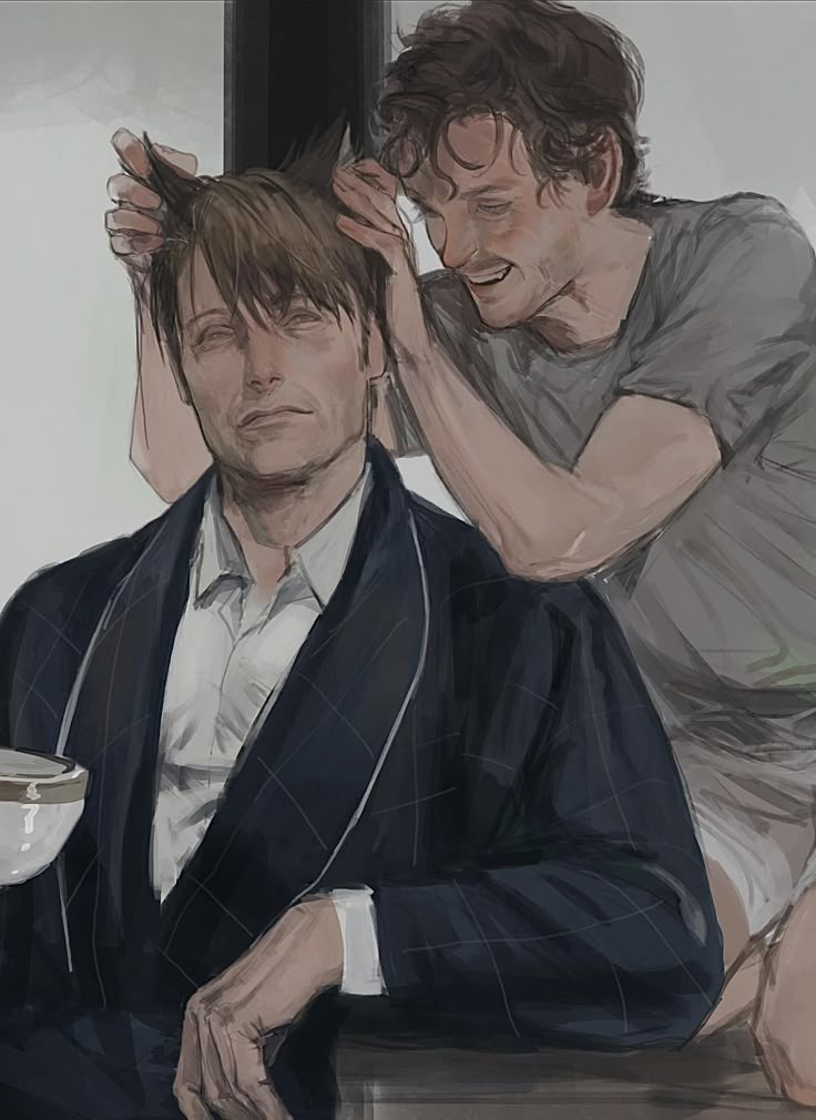 two men sitting next to each other while one is combing another's hair