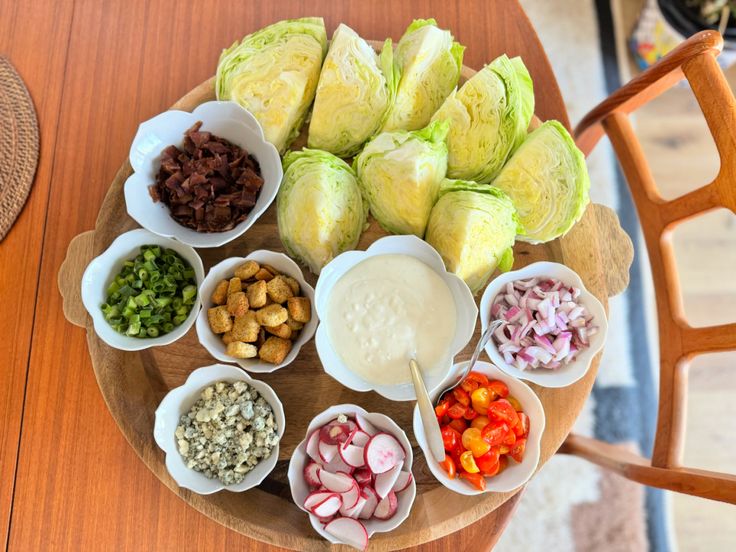 a wooden table topped with bowls filled with different types of vegetables and dips on top of it