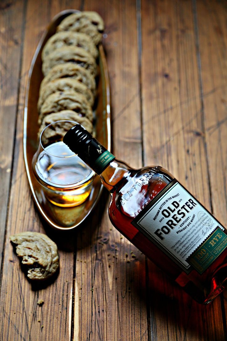 a bottle of whisky sitting on top of a wooden table next to some crackers