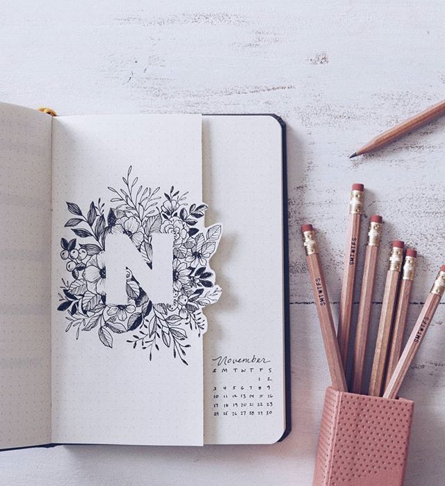 an open notebook sitting on top of a desk next to pencils