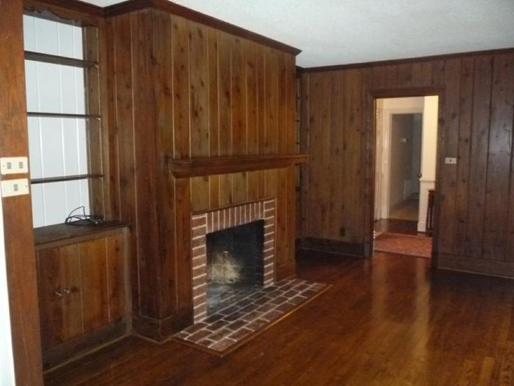 an empty living room with wood paneling and a fire place in the fireplace mantel