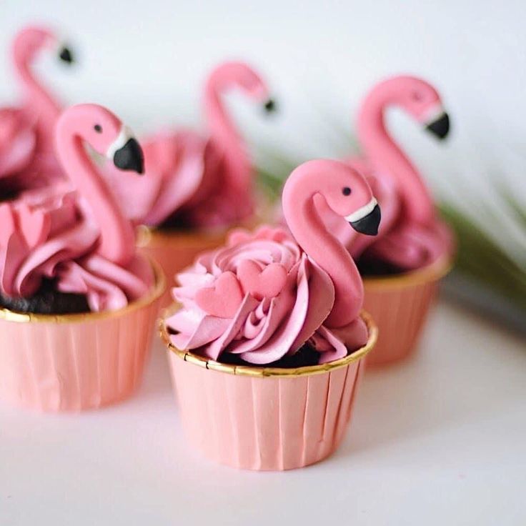 cupcakes with pink frosting and flamingos on top are sitting on a table