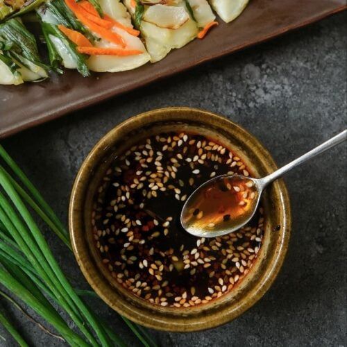 a bowl filled with sesame seeds and vegetables next to some chopsticks on a plate