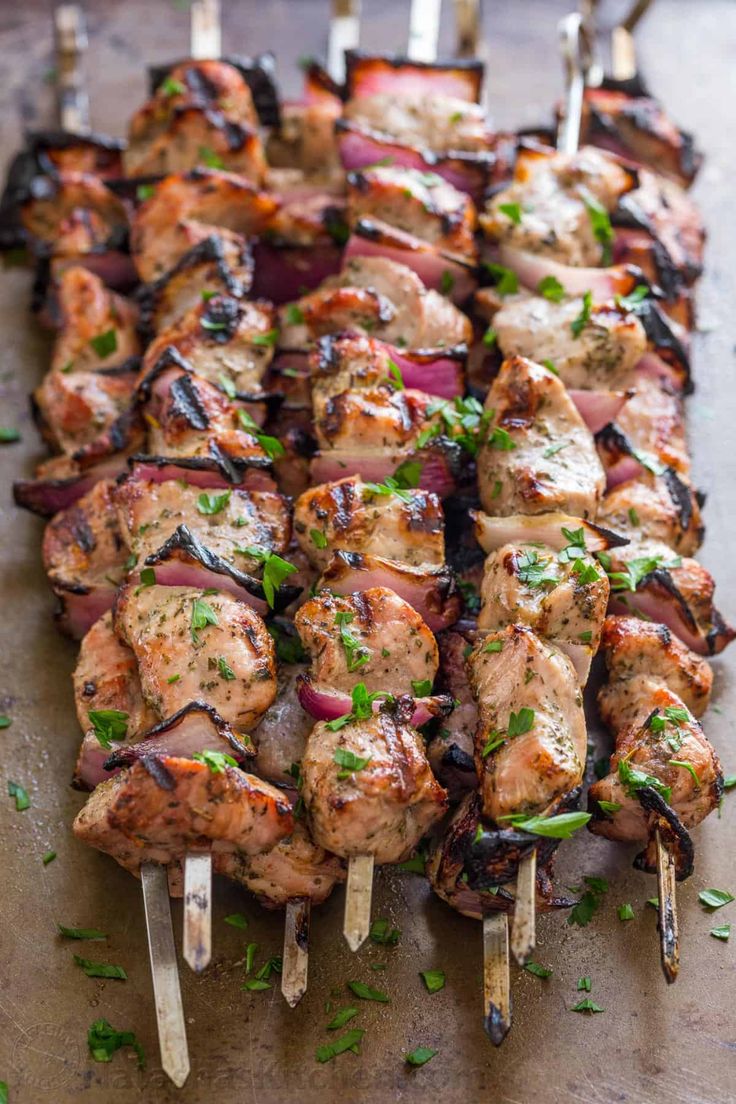 several skewered meats are being cooked on a wooden board with toothpicks