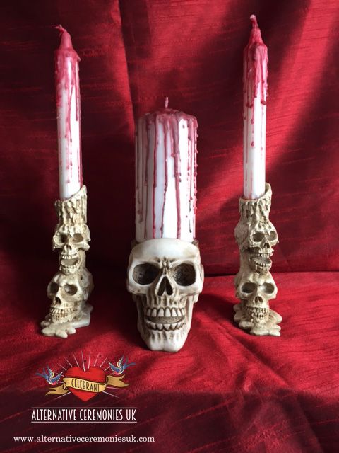 two candles with skulls on them sitting next to each other in front of a red background