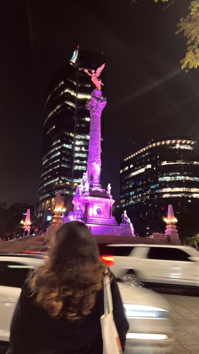 a woman walking down the street in front of a statue