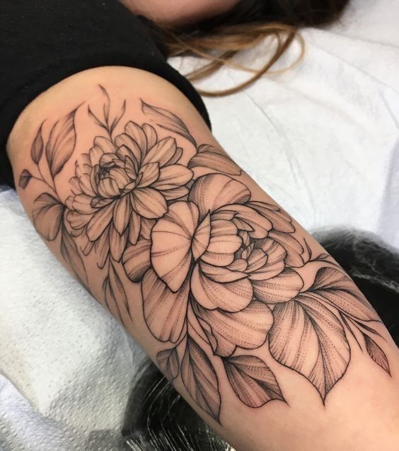 a woman's arm with a flower tattoo on the left side of her arm