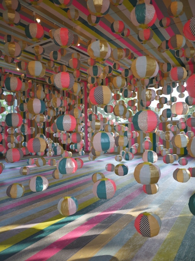 an art installation with multicolored balls hanging from the ceiling and on the ground