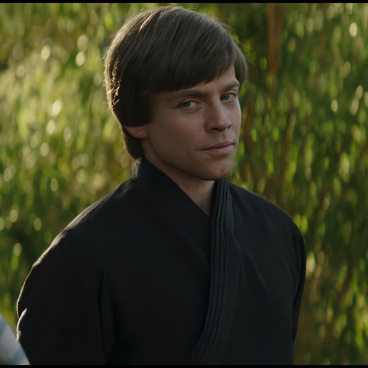 a young man with dark hair wearing a black outfit