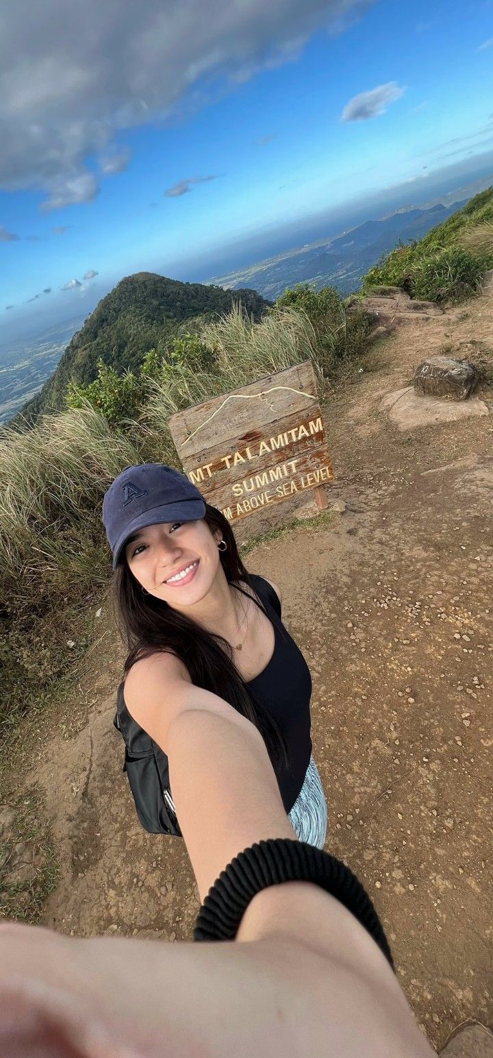 a woman taking a selfie in front of a sign on top of a mountain