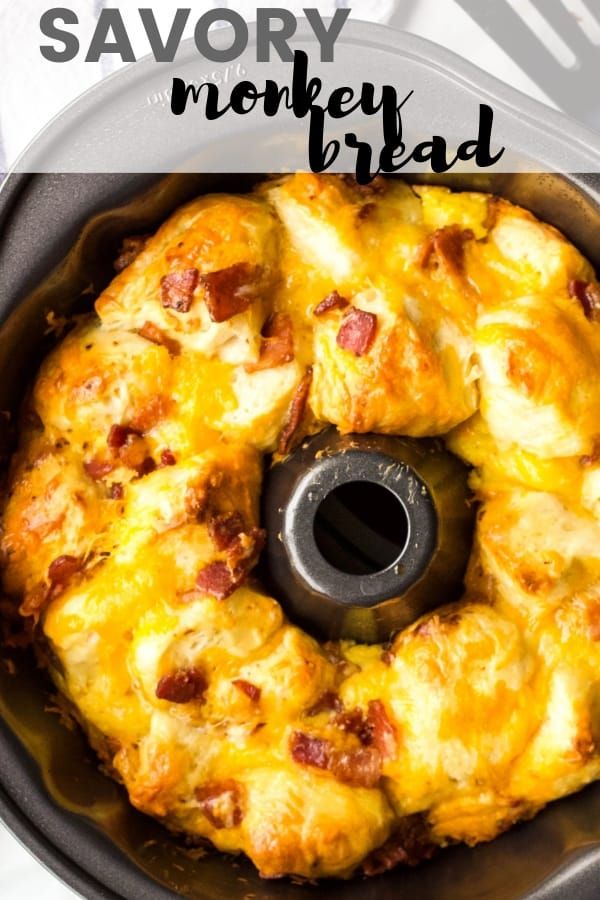 a pan filled with bread covered in cheese and bacon next to a spatula that says savory monkey bread