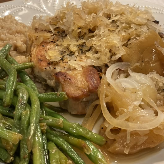 a white plate topped with green beans and meat covered in gravy next to rice