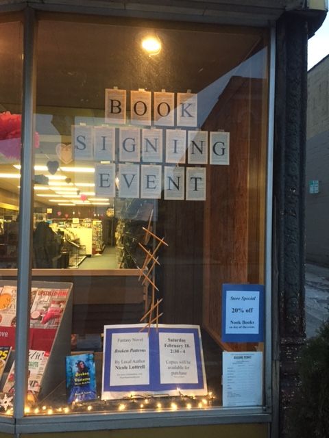 the front window of a book signing event with signs on it and lights in the windows