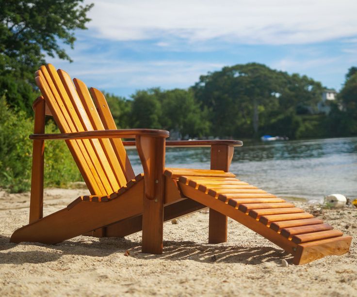 a wooden chair sitting on top of a sandy beach next to a body of water