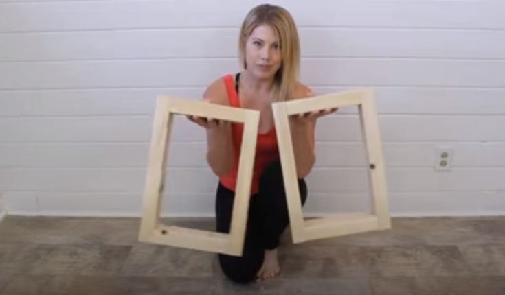 a woman holding two framed pictures in front of her face