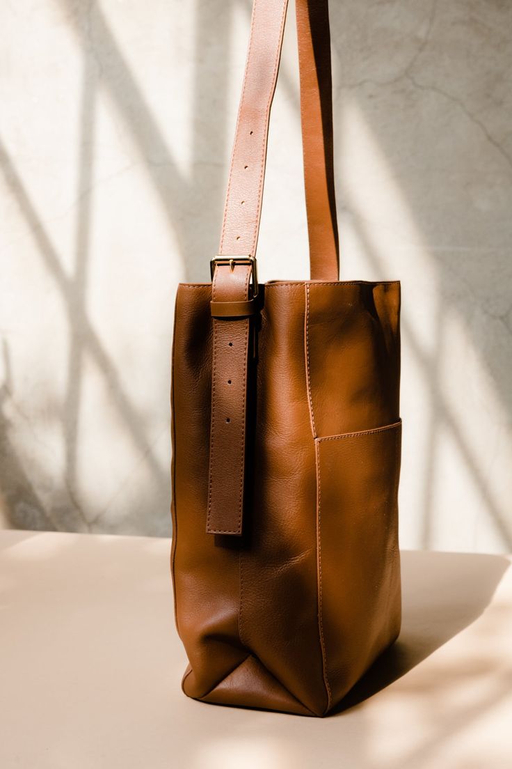 An everyday bag that effortlessly elevates any look, this tall leather tote is as timeless as she is spacious. Featuring our new Lux Full Grain leather with gold hardware details that ensure a polished look time and time again. Complete with exterior pockets and contrast stichting for added organization and style, this tote means business. Lined 2 compartments 2 exterior slip pockets 13.75” H x 9.75” W (at base) x 5” D (at base) Sustainably made from 100% genuine leather Chic Bucket Bag With Leather Lining For On-the-go, Everyday Timeless Leather Shoulder Bag, Timeless Leather Shoulder Bag For Everyday, Workwear Bucket Bag With Leather Lining, Rectangular Vegetable Tanned Leather Bags For Work, Rectangular Vegetable Tanned Leather Work Bag, Everyday Leather Bucket Bag In Timeless Style, Timeless Leather Bag For Work, Timeless Travel Bucket Bag With Soft Leather