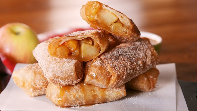 a stack of doughnuts sitting on top of a white napkin next to an apple