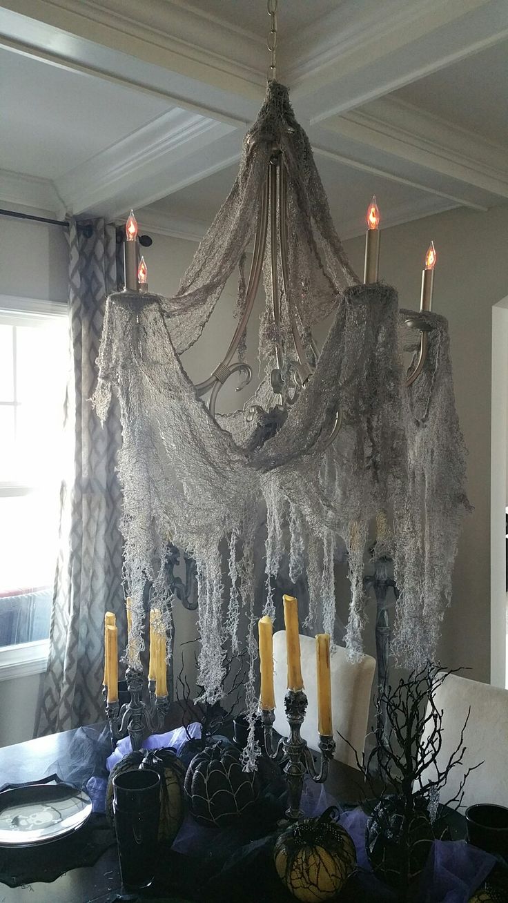 a chandelier hanging from the ceiling over a dining room table with candles on it