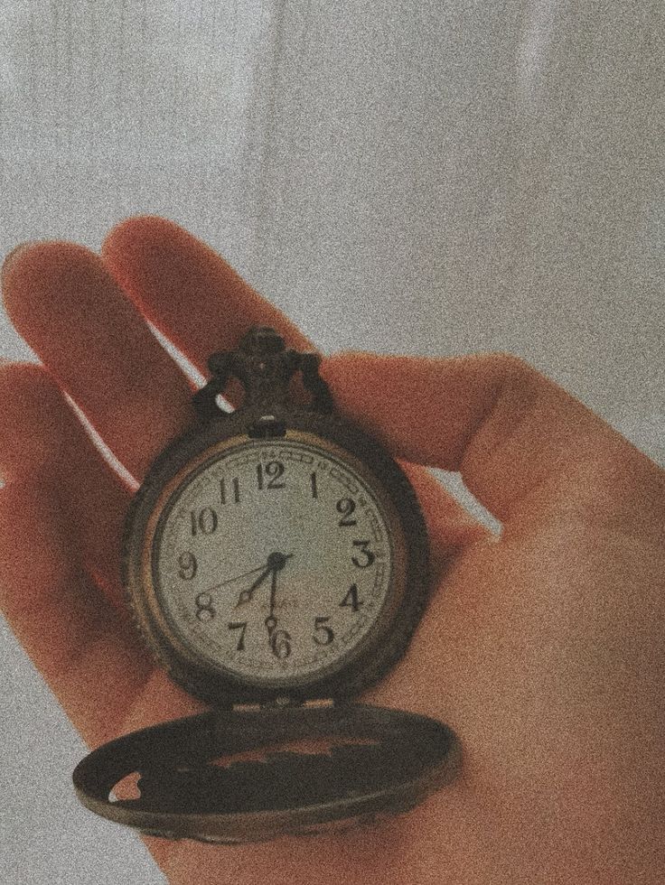 a person holding an antique pocket watch in their left hand, with the time on it's side