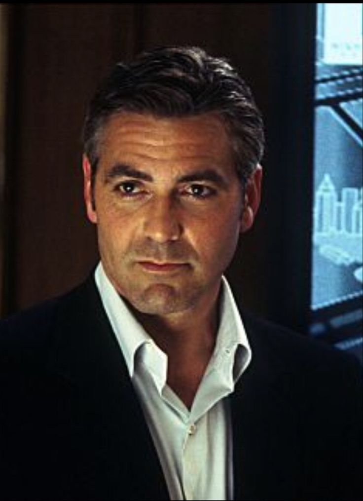 a man in a black suit and white shirt looking at the camera with a serious look on his face