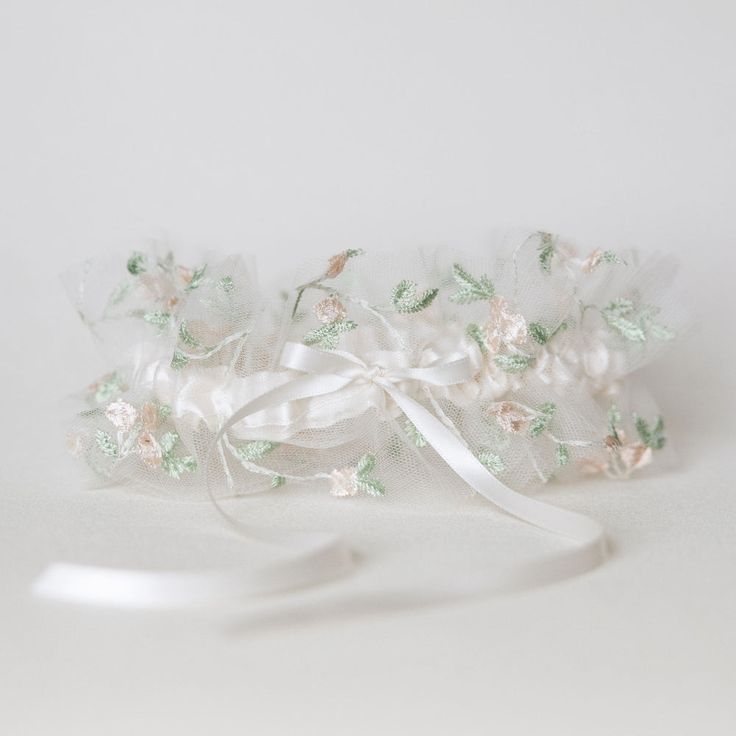 Feminine & fancy-free! Free to be you, just as you are. Our 'Wild Child' style wedding garter heirloom is the perfect wedding heirloom for brides who are inspired by a carefree, effortless, natural bridal style that comes from the purest place of love. Details Production Shipping Sizing Main Garter: Ivory satin background with an overlay of a layer of blush and sage embroidered floral tulle with an ivory satin bow tied in the center with long tails (approximately 2 inches wide).Matching Tossing Garter Belts Bridal, Boho Wedding Garter, Boho Style Bride, Satin Background, Bride Garter, Sage Wedding, Heirloom Wedding, Wedding Garters, Wedding Kiss