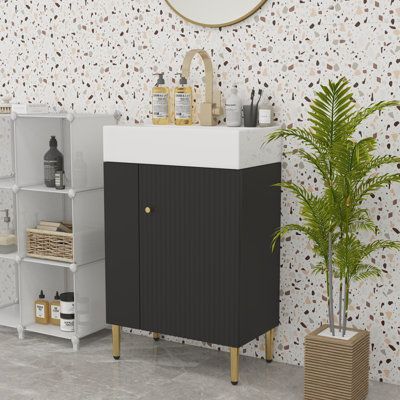 a white sink sitting next to a black cabinet and a potted palm tree in front of a mirror