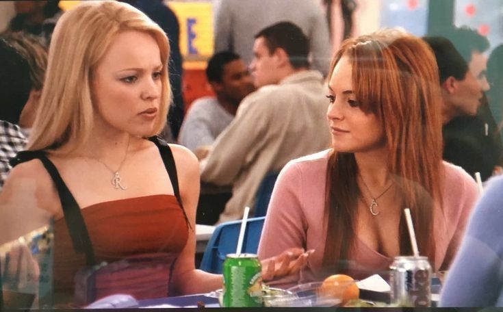 two women sitting at a table in a restaurant talking to each other and drinking beverages