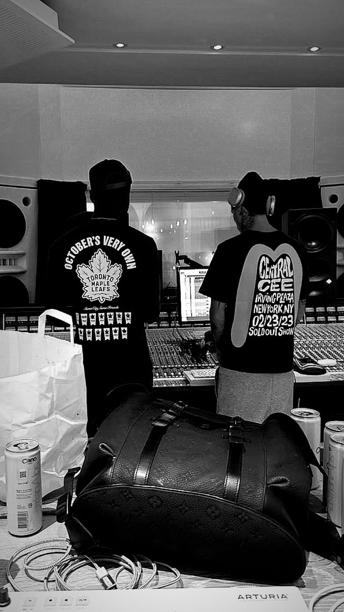 two men standing in front of a computer desk with bags on it and other items around them