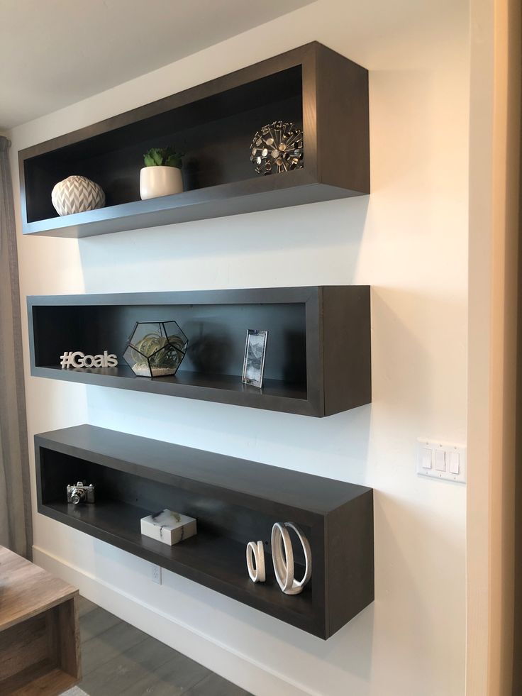 two black shelves are on the wall above each other