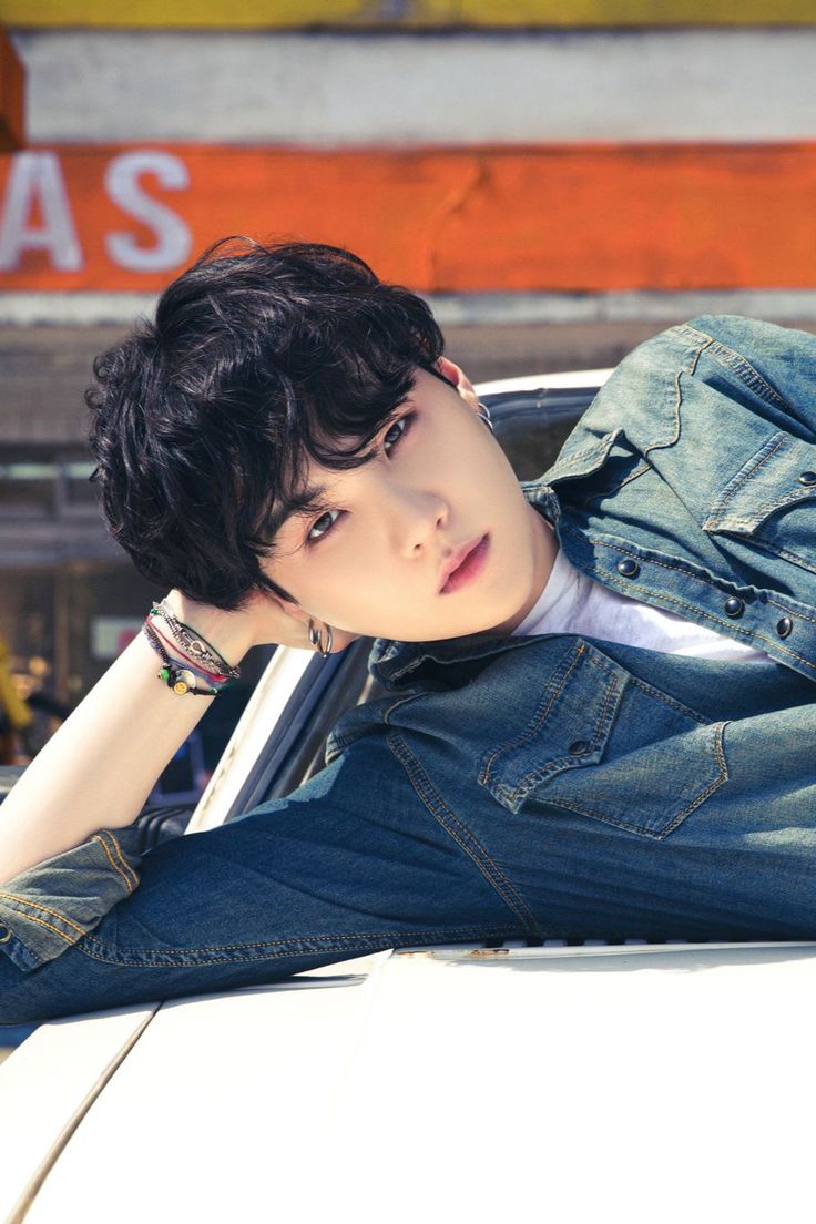 a young man leaning on the hood of a car