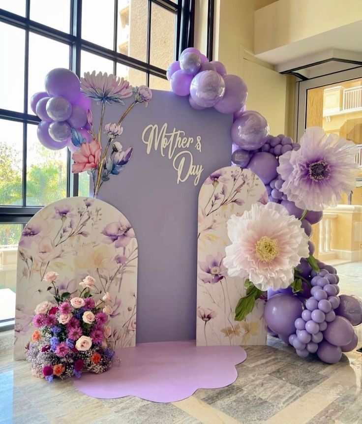 a table topped with balloons and flowers next to a sign that says, mothers day