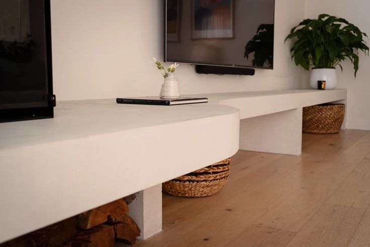 a flat screen tv sitting on top of a white shelf next to a potted plant