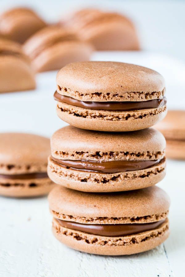 three cookies with chocolate frosting stacked on top of each other in front of more cookies