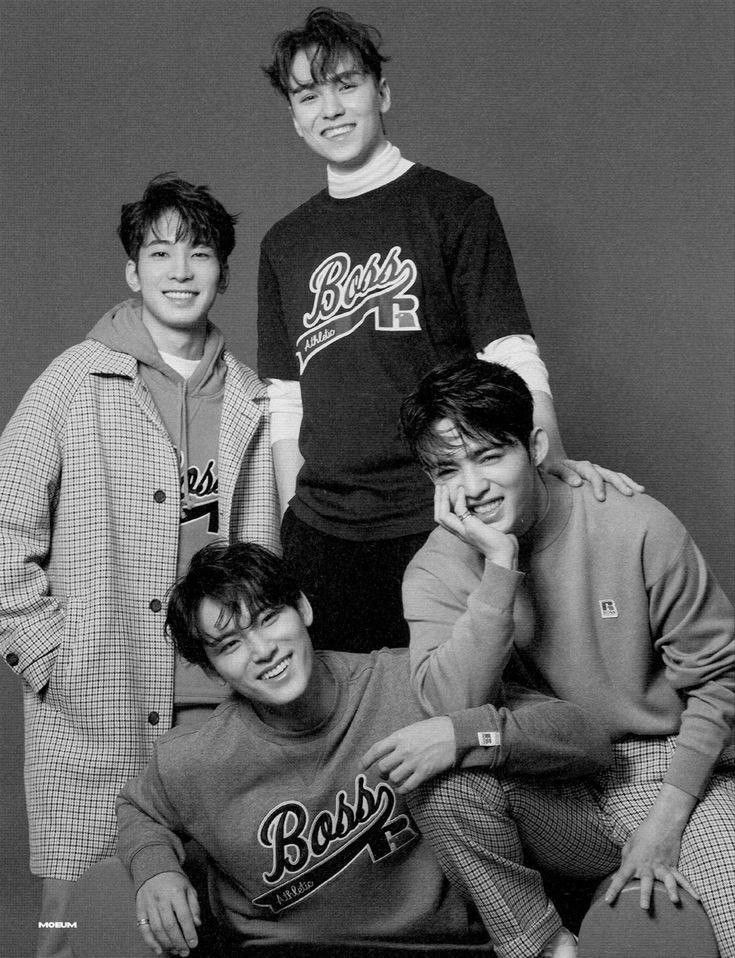 four young men posing for a black and white photo with one man leaning on his head