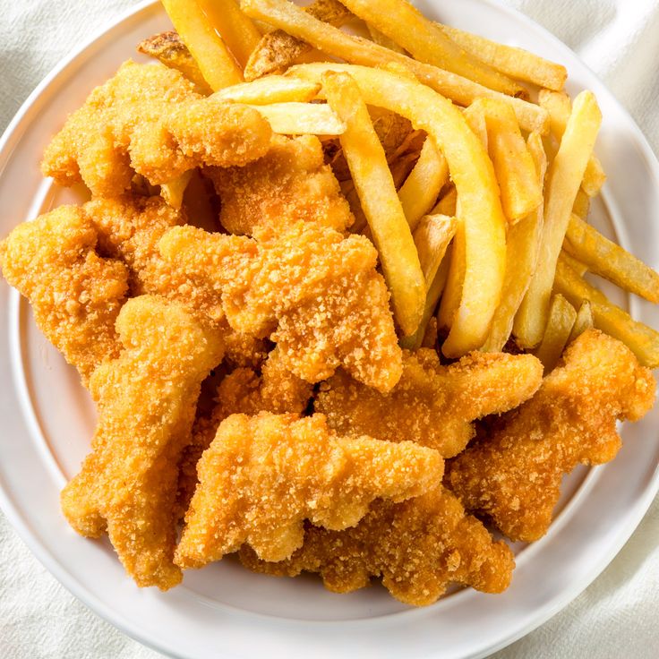 fried chicken and french fries on a plate with a white towel in the back ground