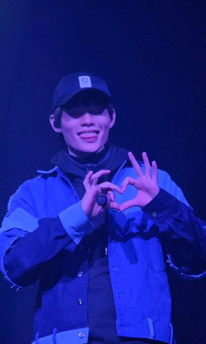 a man standing in front of a black background making the v sign with his hands