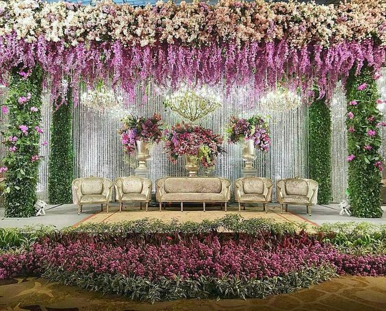 an outdoor wedding setup with flowers on the wall and couches in front of it