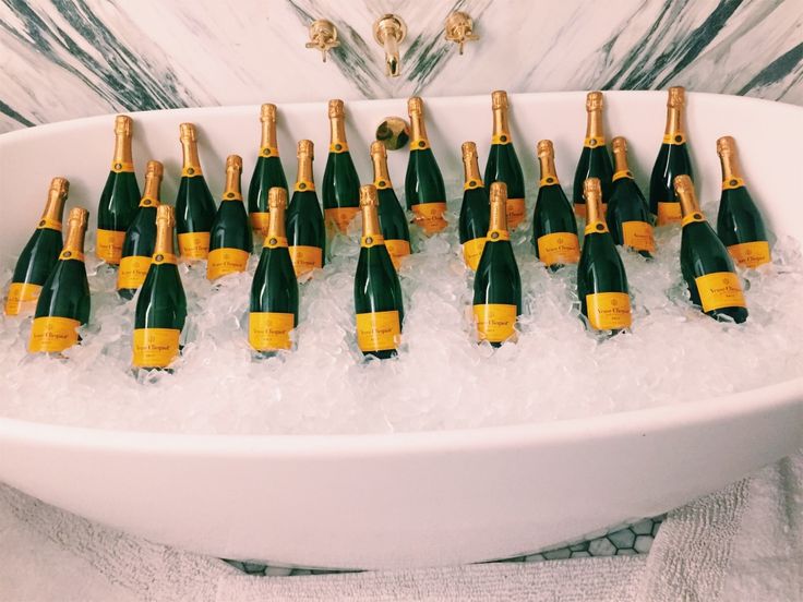 there are many bottles of champagne in the bathtub filled with water and ice cubes