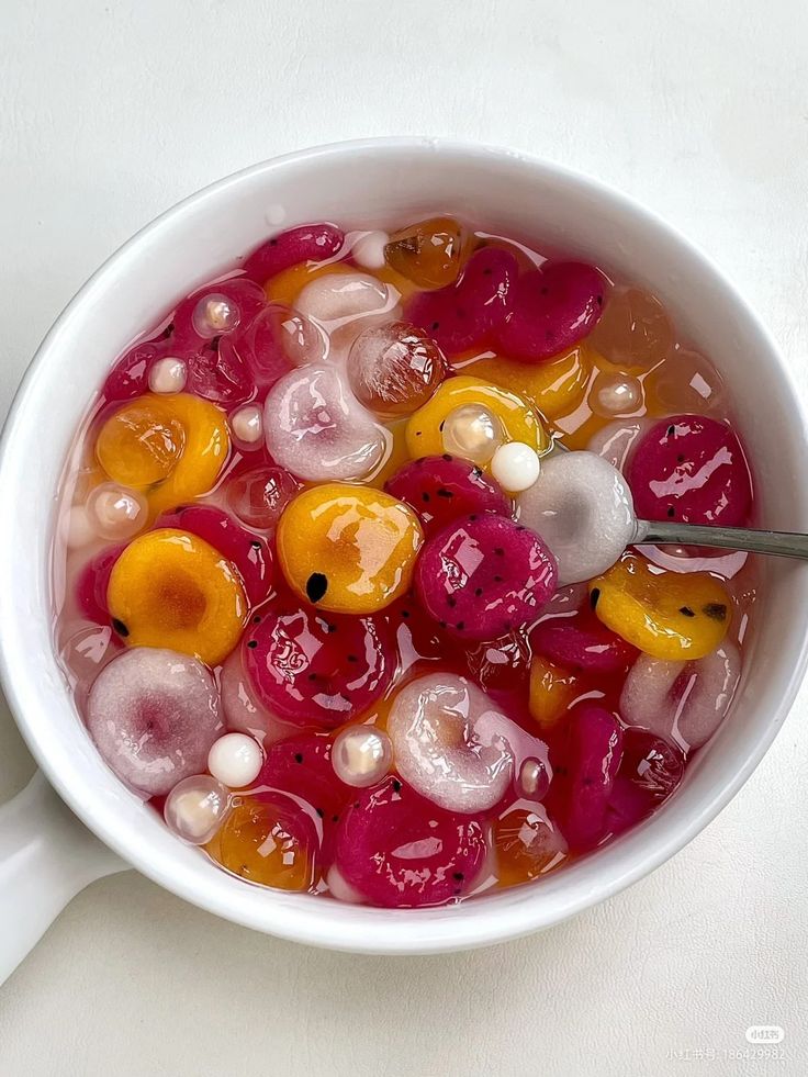 a white bowl filled with jelly and oranges on top of a table next to a spoon