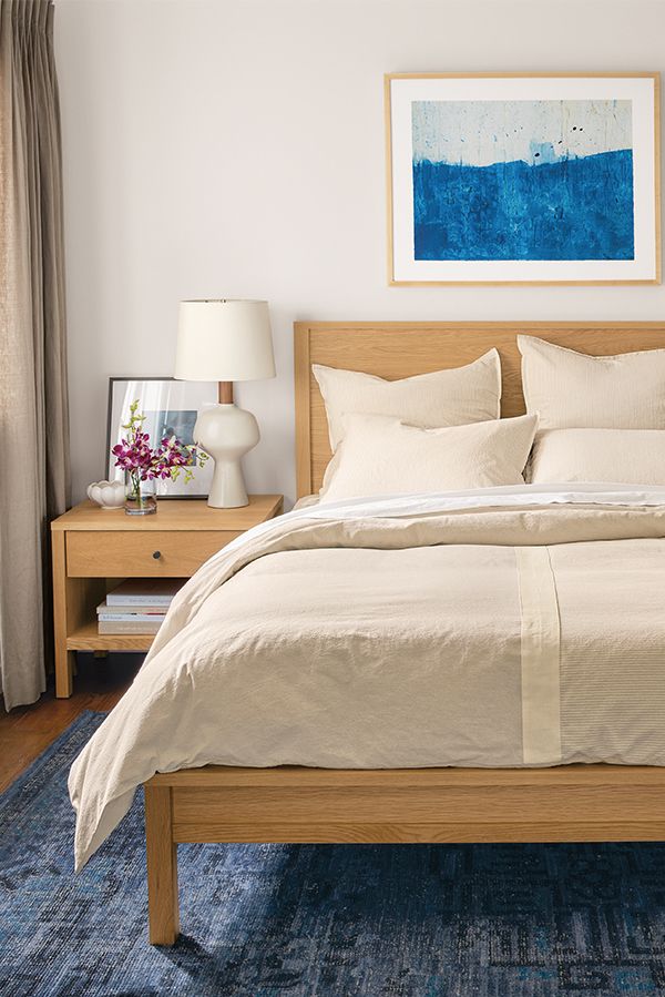 a bedroom with a bed, nightstands and pictures on the wall above it in blue tones