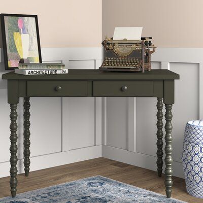 a desk with an old typewriter on it in front of a white wall and blue rug